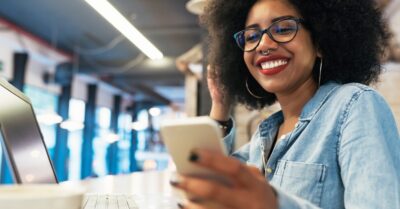 A young woman smiles at her cell phone as she participates in political text banking.