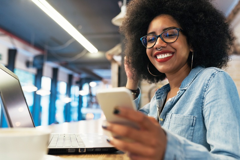 A young woman smiles at her cell phone as she participates in political text banking.