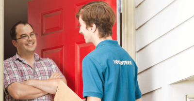 Volunteer canvasser stands at the door of a man’s house to share political campaign information