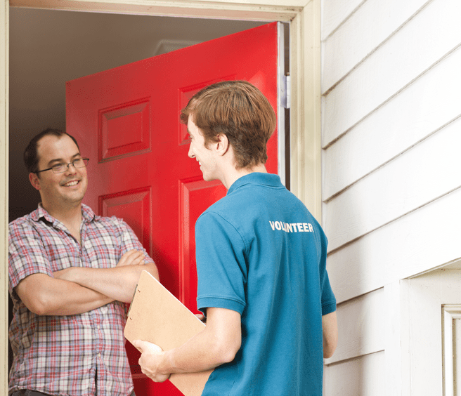 Volunteer canvasser stands at the door of a man’s house to share political campaign information