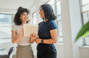 Two women in a campaign office look at a canvassing script example on a tablet.